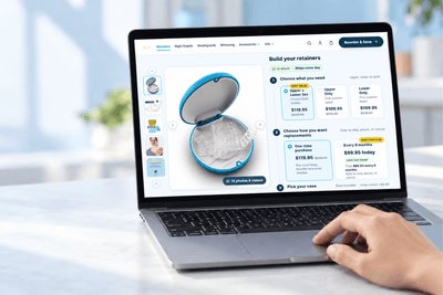 Laptop displaying online clear retainer replacement options for upper, lower, or full sets from SayCheeseClub.