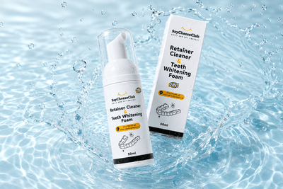 SayCheeseClub 2 in 1 retainer cleaner and teeth whitening foam with product box surrounded by water splashes