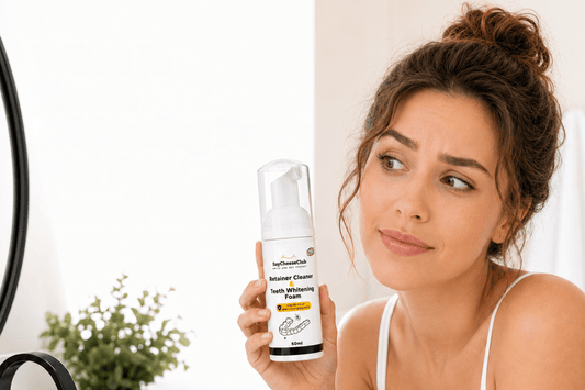 Woman holding SayCheeseClub Retainer Cleaner and Teeth Whitening Foam in front of a bathroom mirror