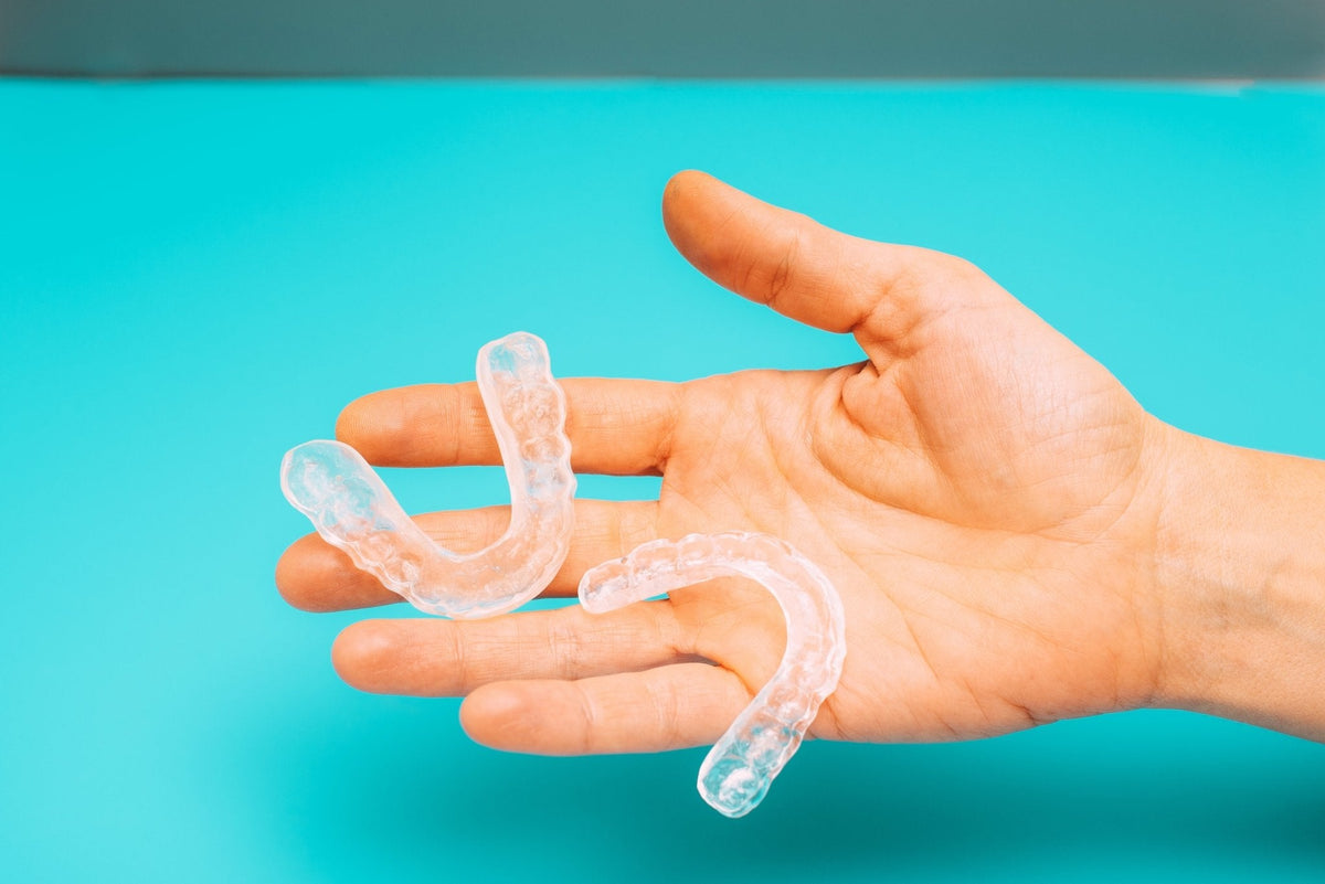 Custom upper and lower bruxism night guard held in a hand