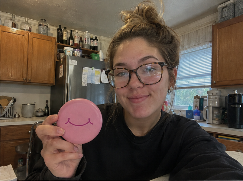 A woman with glasses holds a pink SayCheeseClub case