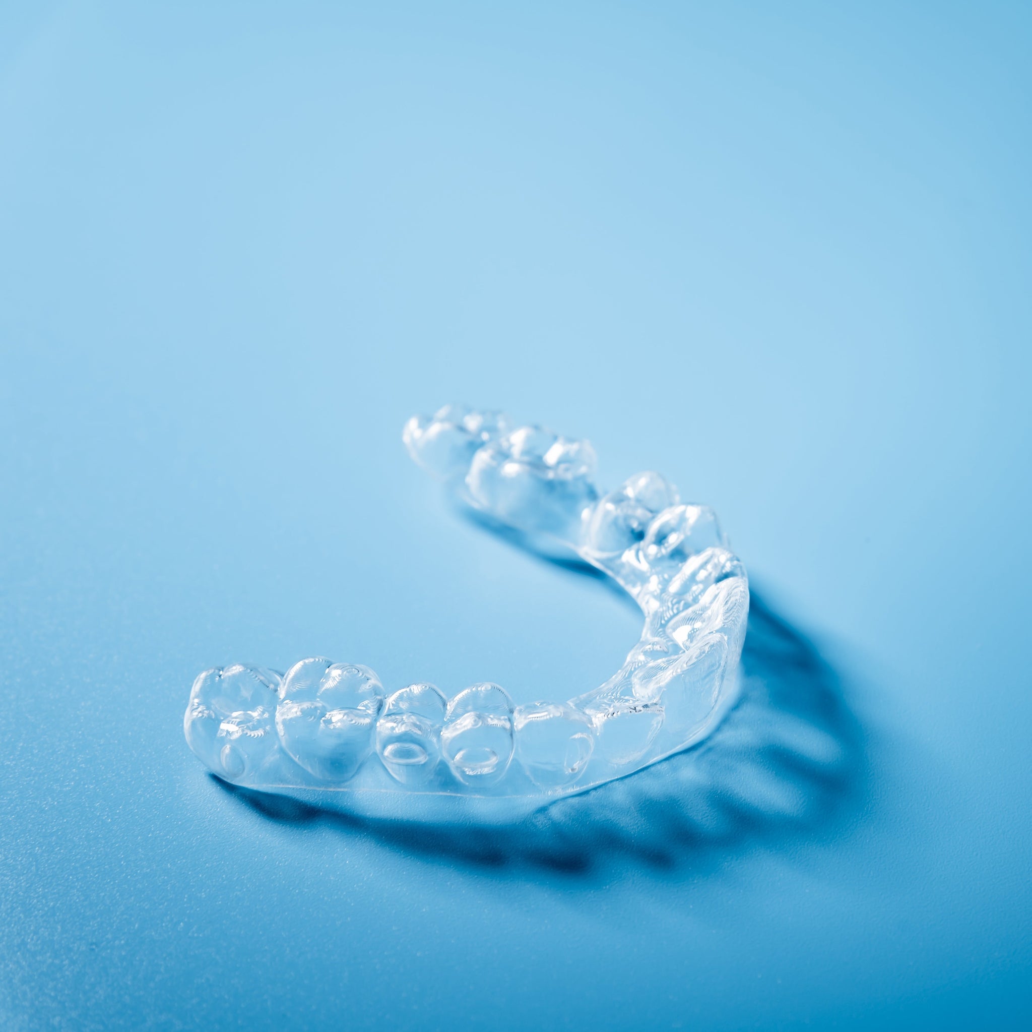 Clear dental night guard on a blue background