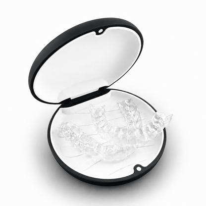 A clear set of transparent dental mouthguards displayed inside an open black and white oval case on a white background.