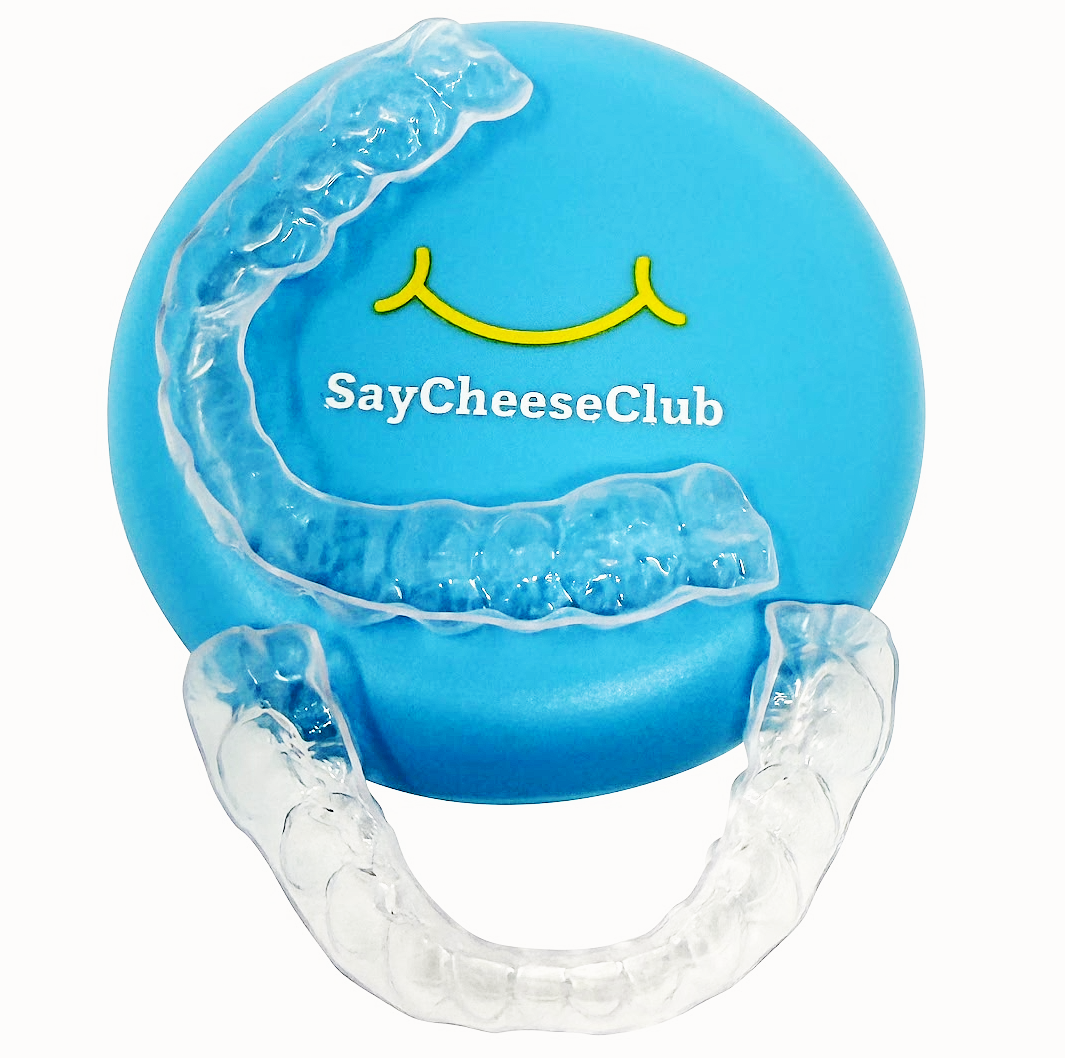 Clear dental retainers on a blue case with 'SayCheeseClub' branding.