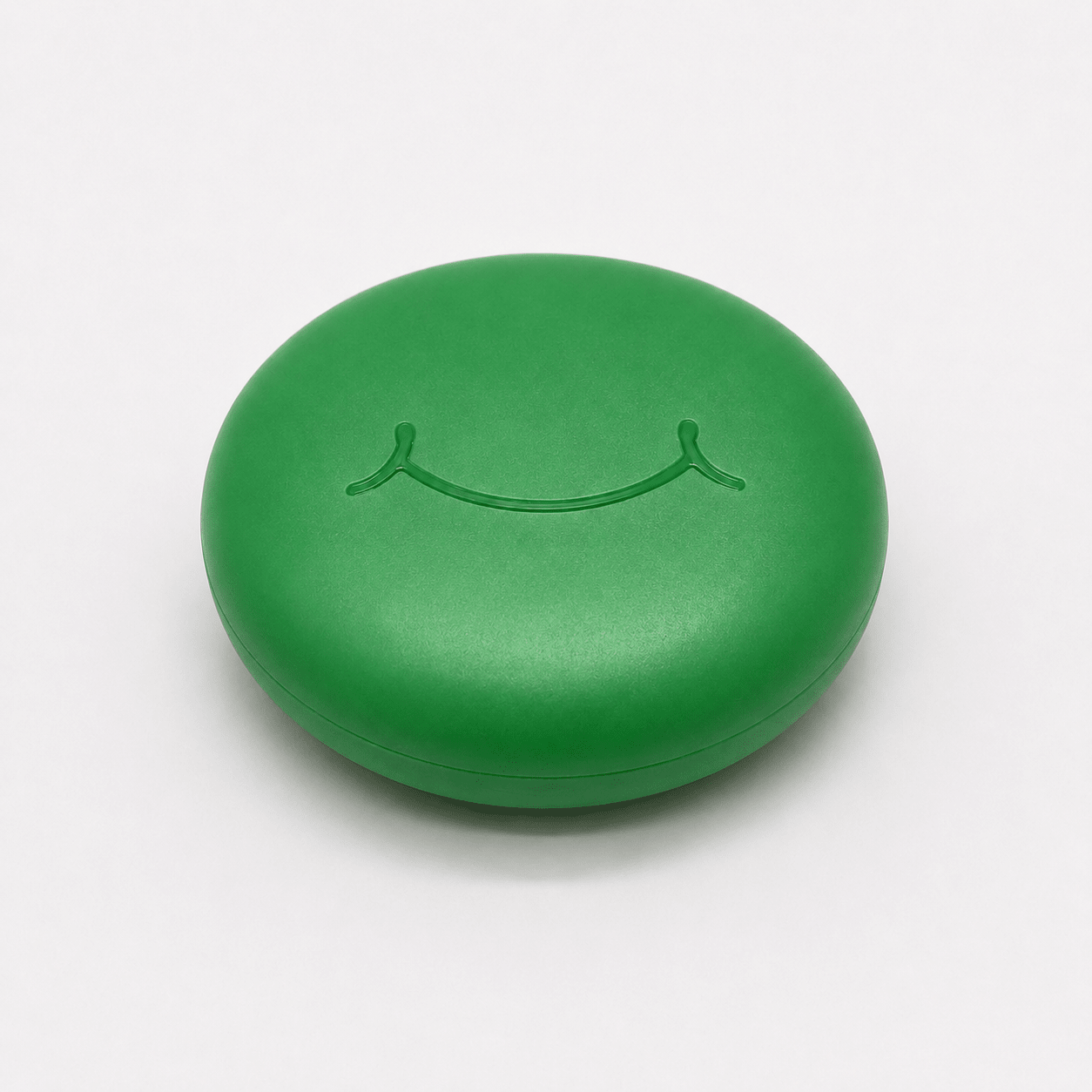 A round green hard retainer case with a simple embossed smiley face on top, photographed on a clean white background.  Also good for clear aligner case.
