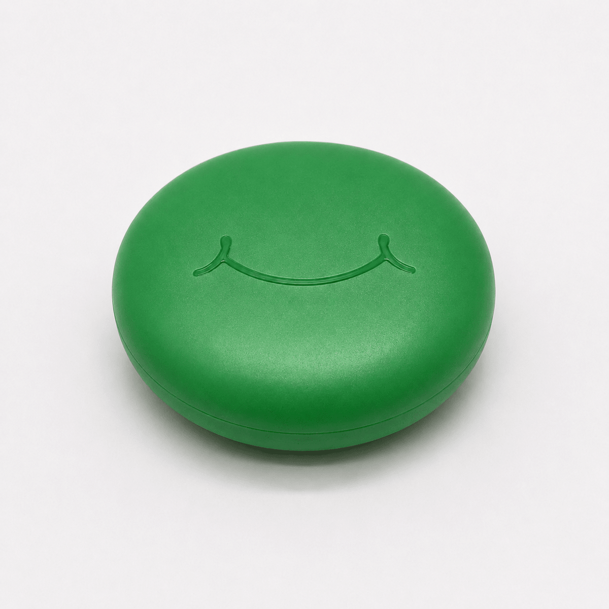 A round green hard retainer case with a simple embossed smiley face on top, photographed on a clean white background.  Also good for clear aligner case.
