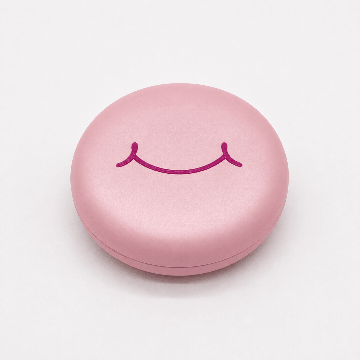 A round pink hard retainer case with a simple embossed smiley face on top, photographed on a clean white background.  Also good for clear aligner case.