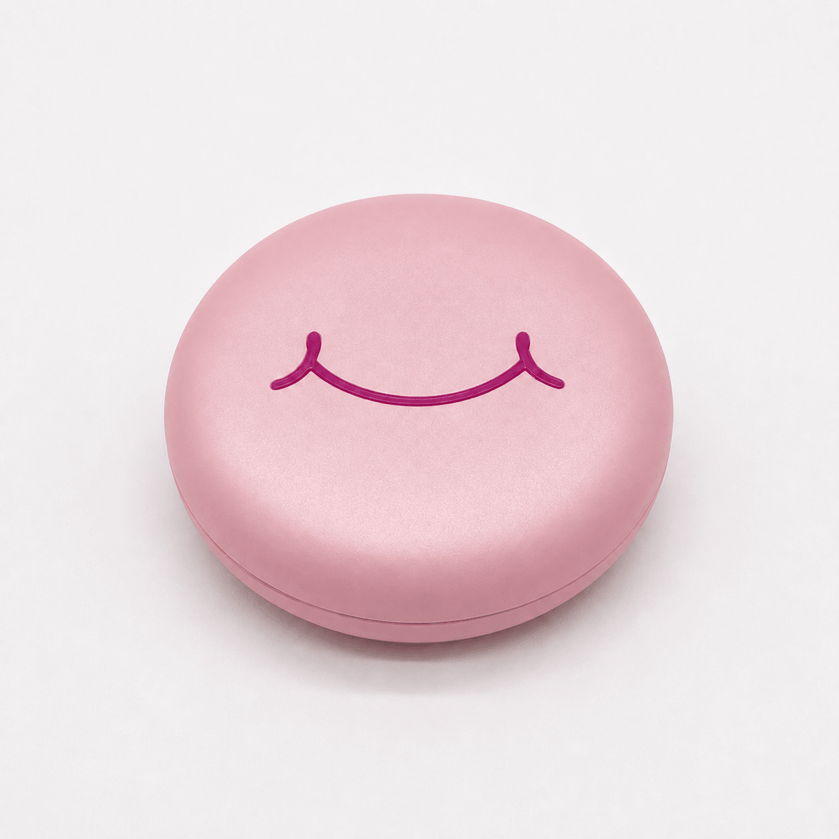 A round pink hard retainer case with a simple embossed smiley face on top, photographed on a clean white background.  Also good for clear aligner case.