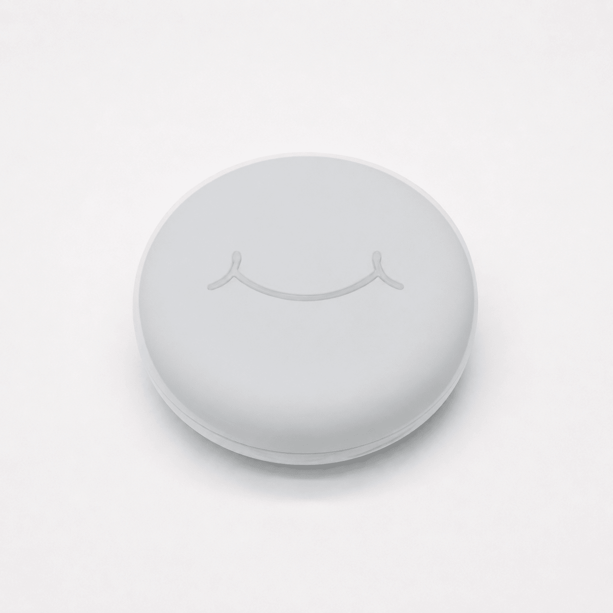 A round white hard retainer case with a simple embossed smiley face on top, photographed on a clean white background.  Also good for clear aligner case.