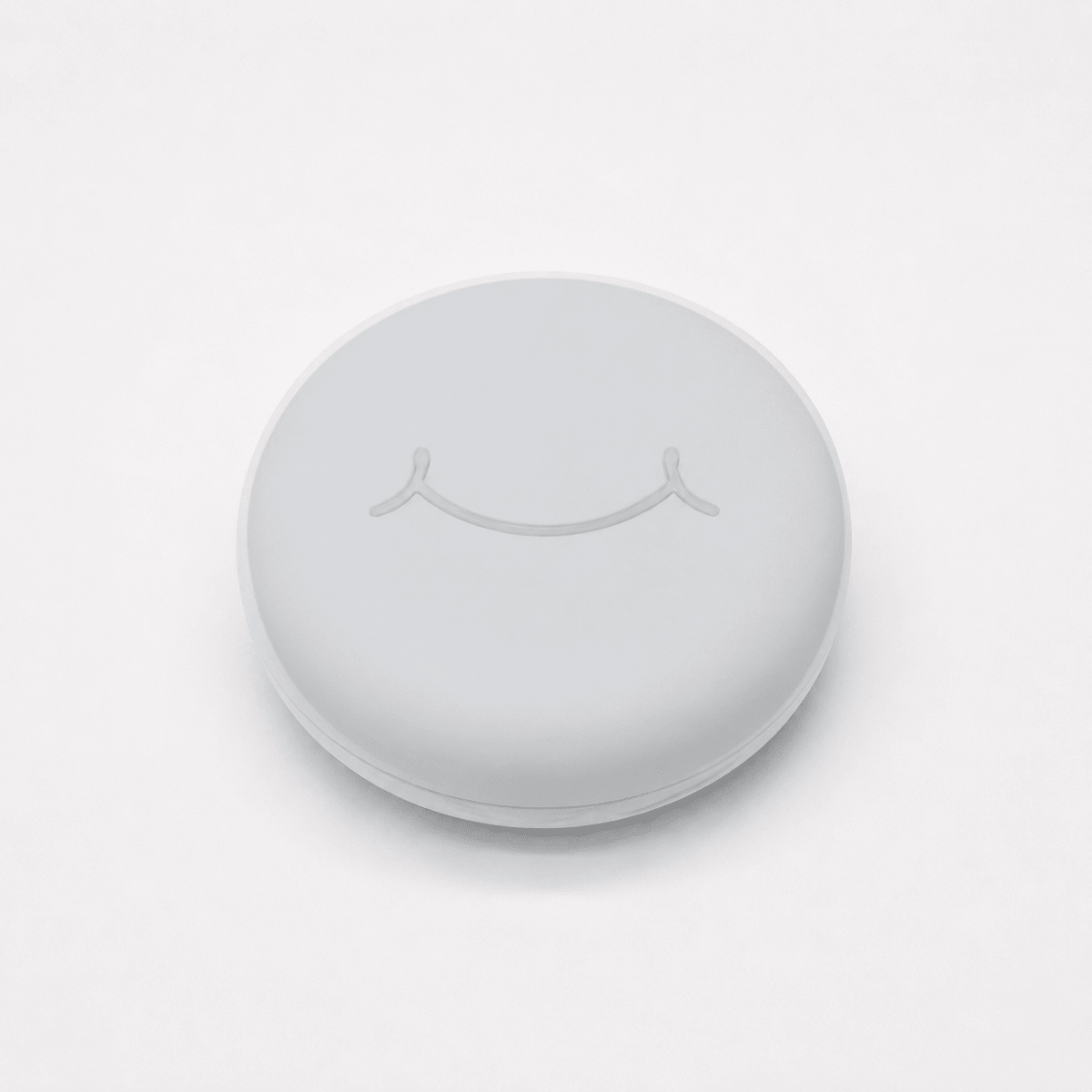 A round white hard retainer case with a simple embossed smiley face on top, photographed on a clean white background.  Also good for clear aligner case.