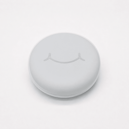 A round white hard retainer case with a simple embossed smiley face on top, photographed on a clean white background.  Also good for clear aligner case.