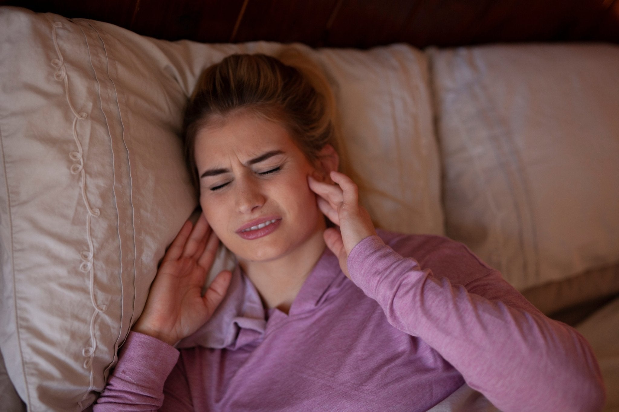 Woman clenching her jaw and experiencing pain caused by bruxism, highlighting the need for SayCheeseClub's brux night guards.