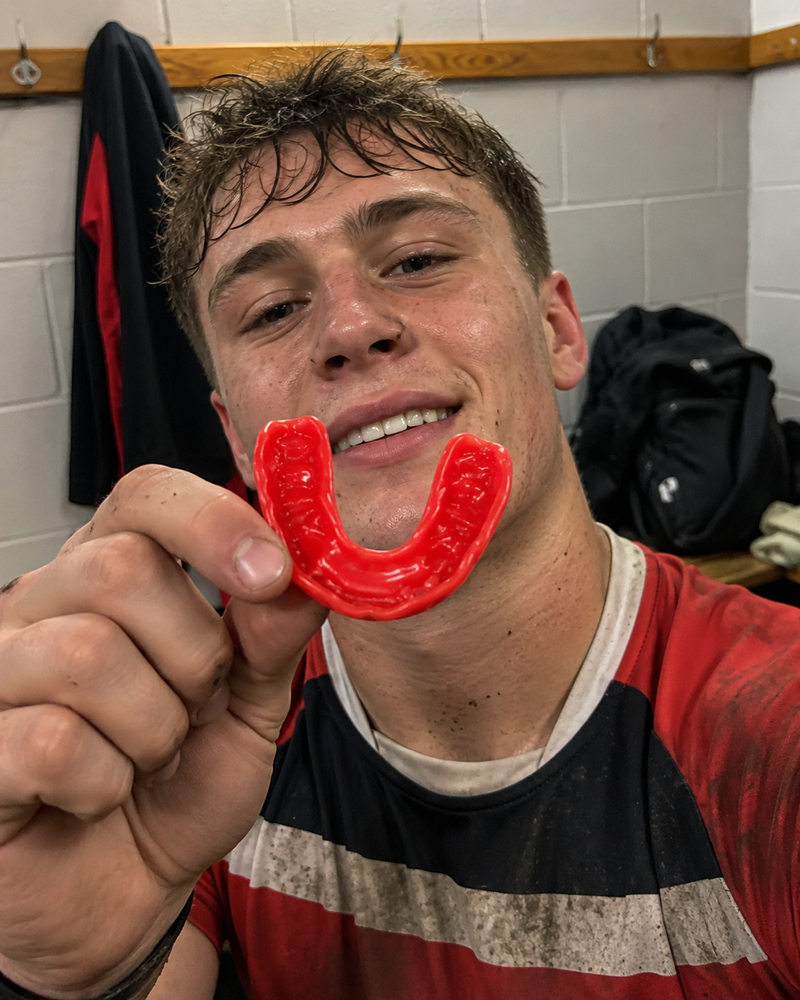 Rugby player holding a red mouthguard in a locker room